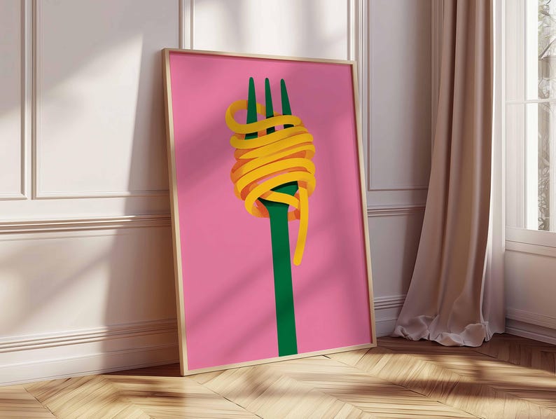 Op de afbeelding: Een ingelijste kunstdruk met een groene vork met gele spaghetti op een roze achtergrond. Het kunstwerk heeft een minimalistische stijl, met een houten lijst. De print leunt tegen een witte muur en een houten vloer. Een moderne kunstwerk.