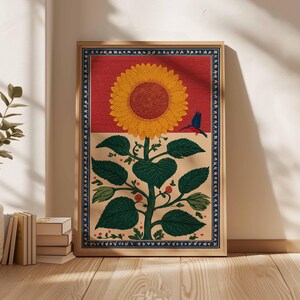 May include: A framed art print featuring a stylized sunflower with a red background and a blue bird. The sunflower has yellow petals and a brown center. The artwork has a beige border with a blue decorative trim.