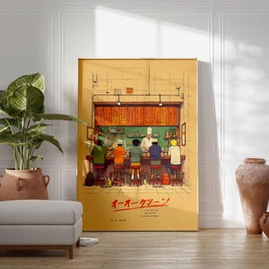 May include: A framed illustration depicts a ramen shop scene with patrons seated at a counter. The artwork features a chef and customers, with Japanese text at the bottom. The color palette includes warm tones of yellow, orange, and brown.
