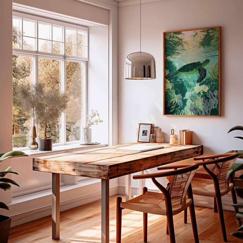 May include: A bright, airy room with a wooden desk and two chairs. A framed sea turtle art piece hangs on the wall. A large window offers a view of trees. A silver pendant light hangs above the desk. Plants and decor add to the room's aesthetic.