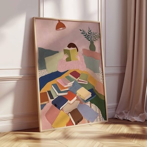 May include: A framed art print depicts a person reading amidst a pile of books. The artwork features a soft color palette with pink, blue, and yellow hues. A lamp hangs above the figure, and a vase of greenery sits in the background.