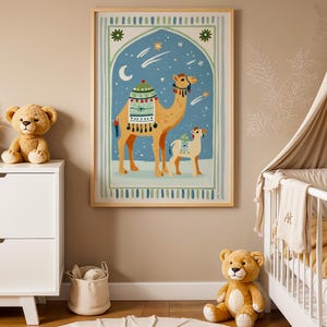 May include: A framed art print featuring a camel and calf under a starry night sky. The artwork has a blue and green arched background with a crescent moon and stars. The camels are tan with decorative saddles. The print is in a light wood frame.