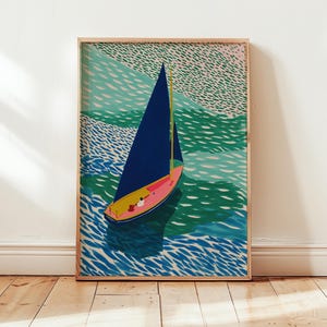 May include: A framed art print depicting a sailboat on water. The boat has a navy blue sail, a pink hull, and a yellow mast. The water is shown in shades of blue and green, with a textured pattern. The artwork is presented in a wooden frame.