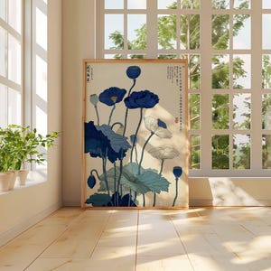 May include: A framed art print featuring a botanical illustration of blue and white flowers with green leaves. The artwork is displayed in a room with a window and natural light. The print has Japanese text.