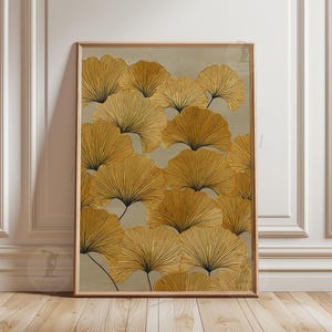 May include: A framed art print featuring a repeating pattern of stylized, golden-yellow ginkgo leaves with black veins against a muted gray-green background. The artwork is displayed in a light brown wooden frame, suitable for home decor.