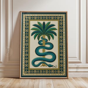 Op de afbeelding: Ingelijste kunstdruk met een turquoise slang die zich om een palmboom wikkelt. Het kunstwerk heeft een crèmekleurige achtergrond met een turquoise en gouden rand. De print zit in een houten lijst.