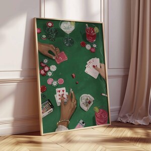 May include: A framed art print depicting a poker game scene. The green felt table is scattered with poker chips, playing cards, and cocktails. Hands with jewelry are visible, holding cards and chips. A cactus and a lighter are also on the table.