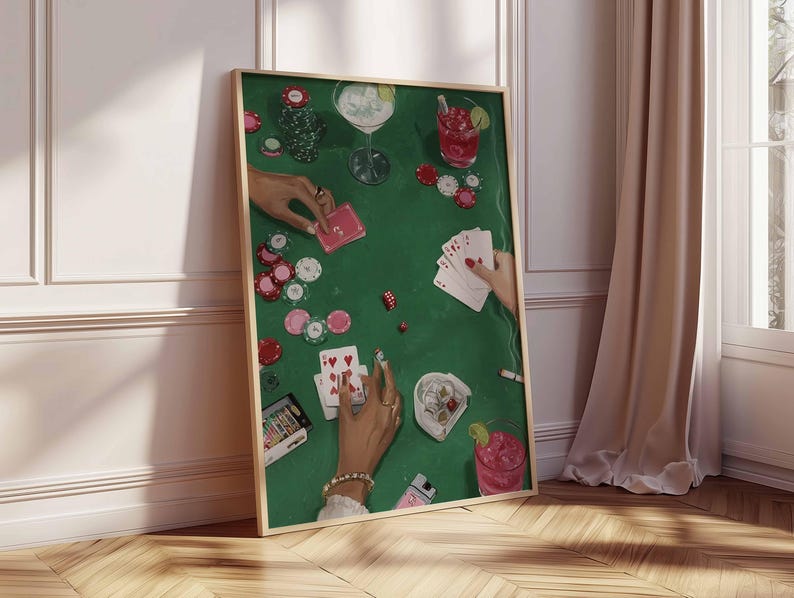 May include: A framed art print depicting a poker game scene. The green felt table is scattered with poker chips, playing cards, and cocktails. Hands with jewelry are visible, holding cards and chips. A cactus and a lighter are also on the table.