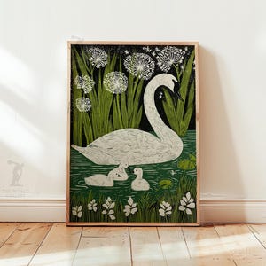 May include: A framed art print featuring a white swan with three cygnets in a pond. The artwork has a green and black background with stylized plants and flowers. The print is in a wooden frame.
