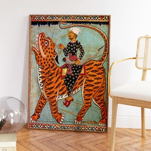 May include: A framed painting depicting a man riding a tiger. The man is wearing a turban and a long robe. The tiger is orange and black with a white background. The painting is surrounded by a decorative border.