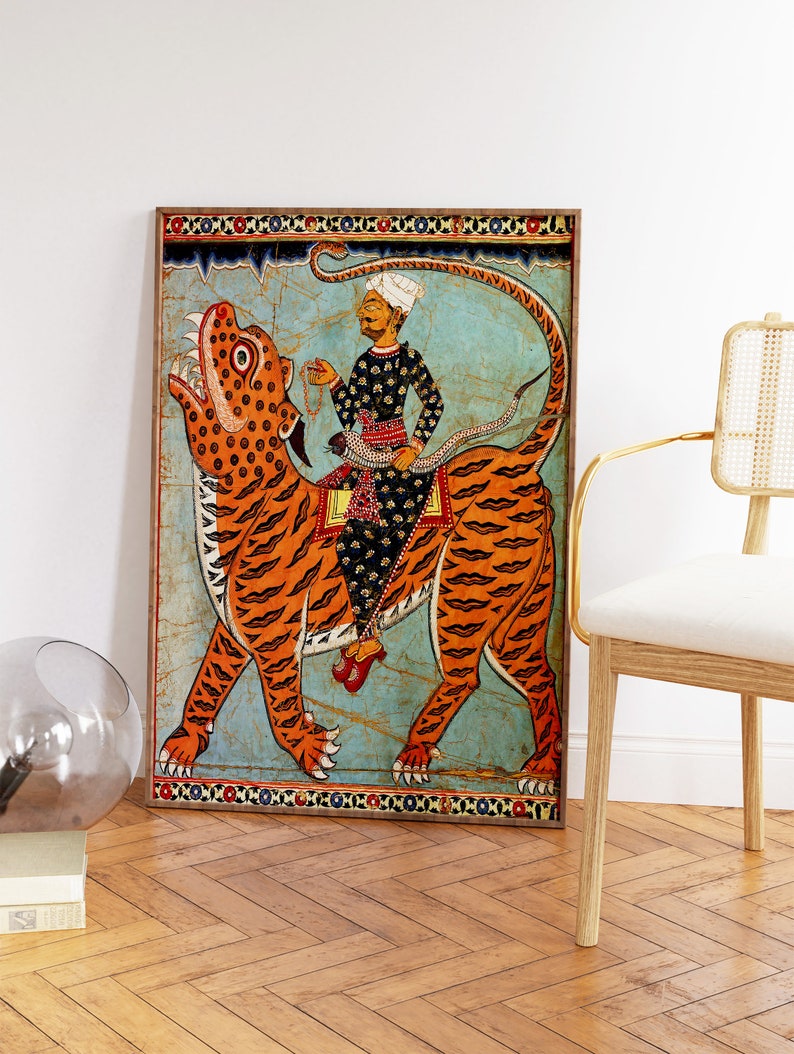 May include: A framed painting depicting a man riding a tiger. The man is wearing a turban and a long robe. The tiger is orange and black with a white background. The painting is surrounded by a decorative border.