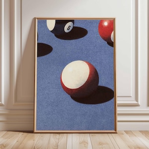 May include: Framed print depicting a retro illustration of snooker balls against a blue backdrop. The balls are red, white, and black, with the number 8 visible on one. The artwork is presented in a wooden frame.