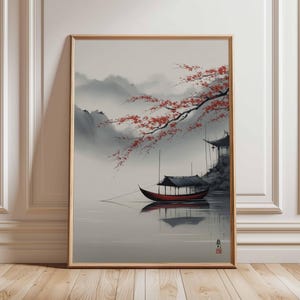 Könnte beinhalten: Gerahmter Kunstdruck, der eine ruhige asiatische Landschaft zeigt. Ein rotes Boot mit schwarzem Dach schwimmt auf ruhigem Wasser und spiegelt die Szene wider. Rote Blüten hängen von einem Ast, und ein traditionelles Gebäude steht am Ufer. Berge sind im Hintergrund zu sehen.