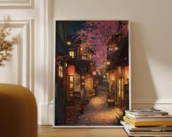 May include: A framed print showing a Japanese street scene at night. The artwork depicts a cobblestone street lined with buildings, lit by lanterns and shop lights. Cherry blossom trees overhang the street, with pink flowers. A stack of books rests on the floor.