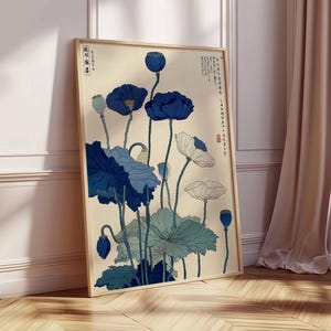 May include: Framed art print featuring a botanical illustration of blue and white poppies. The artwork has a vintage aesthetic with Japanese-inspired elements. The print is displayed against a cream-colored background, with a wooden frame.