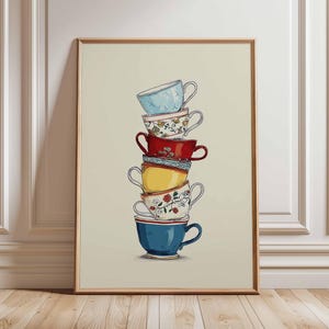 May include: A framed print showing a stack of six teacups. The teacups are in various colours, including blue, red, and yellow, and decorated with floral patterns. The artwork is set against a neutral background and framed in a light brown wooden frame.