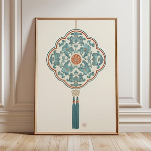 May include: Framed artwork with a teal and orange floral design on a cream backdrop. The design is symmetrical, in a quatrefoil shape with a central circular element. Teal tassels hang below. The artwork is in a wooden frame, suitable for interior decor.