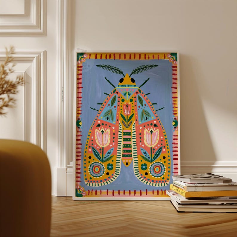 Pode incluir: Uma impress&atilde;o art&iacute;stica emoldurada com uma ilustra&ccedil;&atilde;o colorida de tra&ccedil;a. A tra&ccedil;a tem um fundo azul com um design detalhado em rosa, amarelo e verde-azulado. A obra de arte &eacute; emoldurada em uma borda branca e repousa contra uma parede branca.