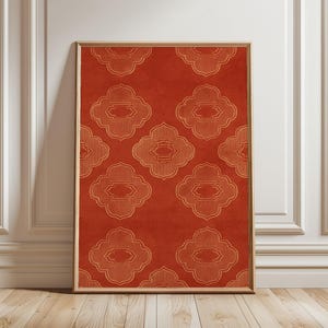 Può includere: Una stampa artistica da parete rettangolare in una cornice di legno chiaro con uno sfondo rosso terracotta intenso e un motivo ripetuto di forme geometriche a quattro lobi color oro, ciascuna contenente dettagli a linee verticali.