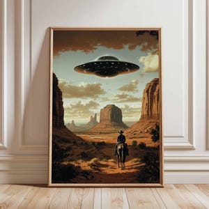 May include: Framed art print showing a desert scene with a cowboy riding a horse, silhouetted against mesas and a hovering UFO. The artwork uses warm earth tones and a dramatic sky, creating a surreal scene.