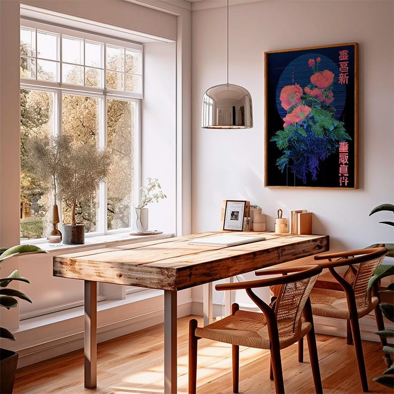 May include: A well-lit room with a large wooden table and two chairs. A framed floral print hangs on the wall. A large window offers a view of trees. A silver pendant light hangs above the table. The chairs have woven seats and wooden frames.