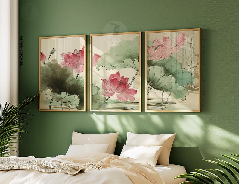 May include: Three framed art prints featuring watercolor paintings of pink lotus flowers and green leaves. The artwork is set against a neutral background, with gold frames. The prints are displayed on a green wall above a bed with white bedding.