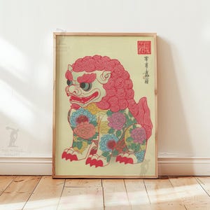 May include: Framed print of a stylized lion-like creature with a red mane and floral patterns. The artwork features a cream background and is displayed in a wooden frame. The lion has a fierce expression and is adorned with colorful flowers.