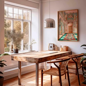 May include: A well-lit home office with a large wooden desk and two woven chairs. A framed artwork depicting an ornate interior scene hangs on the wall. A large window offers a view of the outdoors. A modern silver pendant light hangs above the desk.