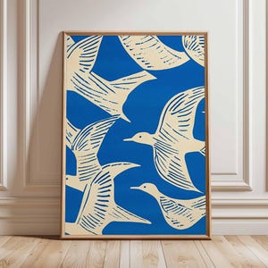 May include: A framed art print featuring a pattern of cream-colored birds against a vibrant blue background. The birds are depicted in a stylized, minimalist design, with visible wing details. The artwork is encased in a wooden frame, suitable for wall decor.