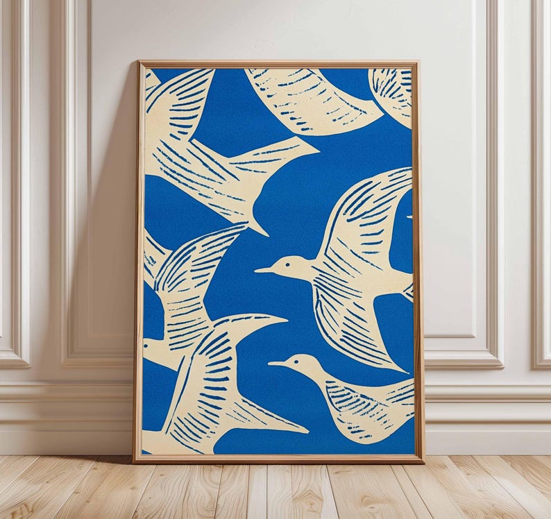 May include: A framed art print featuring a pattern of cream-colored birds against a vibrant blue background. The birds are depicted in a stylized, minimalist design, with visible wing details. The artwork is encased in a wooden frame, suitable for wall decor.