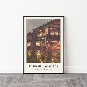 May include: A framed print of a painting by Hiroshi Yoshida titled "Evening After Rain, 1926". The painting depicts a street scene in Japan with a building lit up by lanterns and reflections in the wet street.