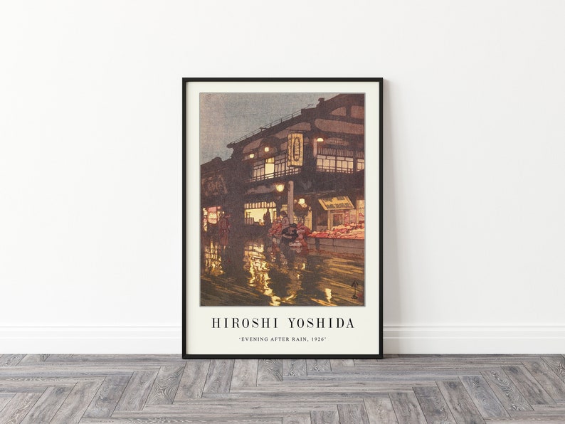 May include: A framed print of a painting by Hiroshi Yoshida titled "Evening After Rain, 1926". The painting depicts a street scene in Japan with a building lit up by lanterns and reflections in the wet street.