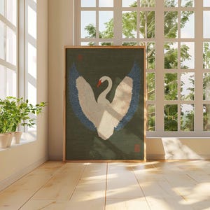Pode incluir: Uma obra de arte emoldurada com um cisne estilizado com as asas abertas. O cisne &eacute; branco com detalhes azuis nas asas e um bico vermelho, sobre um fundo verde escuro. A obra de arte &eacute; exibida em uma sala com luz natural.