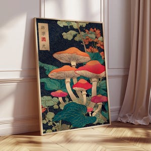May include: A framed art print depicting stylized mushrooms in red, orange, and pink against a dark blue backdrop. The artwork includes green foliage and Japanese text. The print is displayed on a wooden floor. The frame is a light brown color.