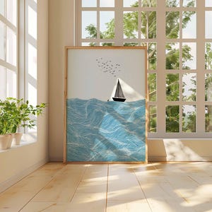 May include: A framed art print depicts a sailboat on a wavy sea under a clear sky with birds. The artwork is in a wooden frame and leans against a wall near a window. The color palette includes shades of blue, white, and black.