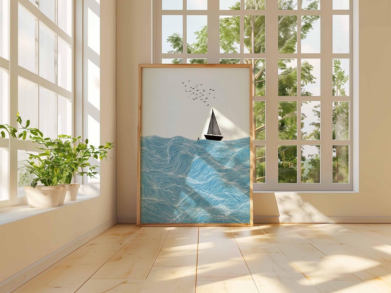 May include: A framed art print depicts a sailboat on a wavy sea under a clear sky with birds. The artwork is in a wooden frame and leans against a wall near a window. The color palette includes shades of blue, white, and black.