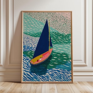 May include: A framed art print depicting a sailboat on water. The boat features a navy blue sail, a pink hull, and a yellow mast. The water is rendered in shades of blue and green, with a textured pattern. The artwork is displayed on a wooden floor.