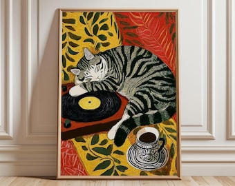 May include: A framed art print featuring a sleeping cat on a record player. The cat has gray and black stripes. A cup of coffee sits nearby. The background has yellow and red floral patterns. The artwork is in a wooden frame.