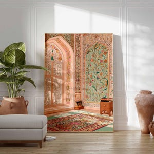 May include: A large framed artwork showing an ornate interior scene with floral and architectural details in soft pinks, greens, and golds. A large potted plant, a grey ottoman, and terracotta vases are in the foreground. The artwork leans against a white wall.