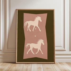May include: A framed rectangular wall art print featuring a dark olive green background with a central vertical dusty rose shape. Two cream-colored horse silhouettes are depicted in profile, one above the other, separated by a small star icon.