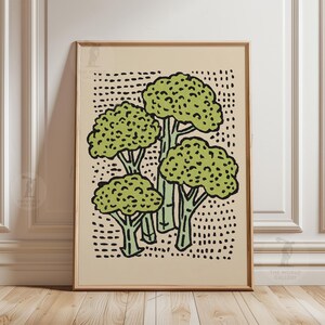 Könnte beinhalten: Gerahmter Kunstdruck mit einer stilisierten Illustration von vier Brokkoliröschen. Der Brokkoli ist grün mit schwarzen Umrissen, vor einem beigefarbenen Hintergrund mit schwarzen Punkten. Das Kunstwerk ist in einem goldfarbenen Rahmen präsentiert.