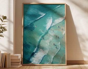 May include: A framed art print depicting an aerial view of a turquoise ocean with white-capped waves. Surfers are scattered throughout the water. The artwork is displayed in a room with natural light and a wooden floor.