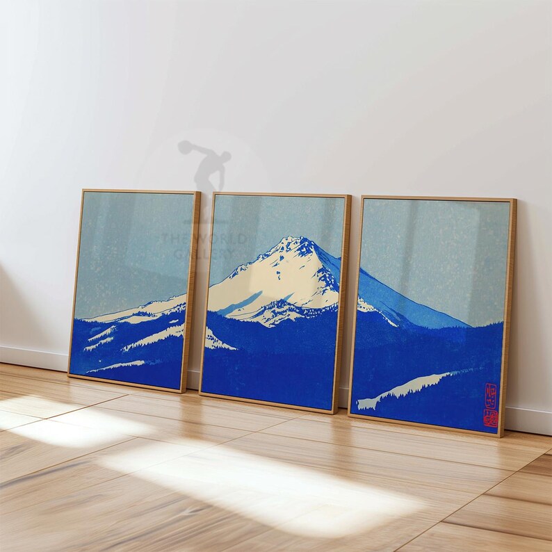 K&ouml;nnte beinhalten: Drei gerahmte Drucke mit einer Berglandschaft in Blau- und Cremet&ouml;nen, im Stil japanischer Holzschnitte. Die Rahmen sind helles Holz. Die Drucke lehnen an einer wei&szlig;en Wand.