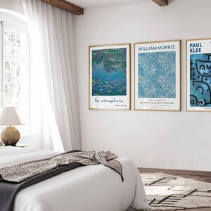 May include: Three framed art prints on a white wall. The prints feature artwork with blue and white colour schemes. The first print has the text "les n&eacute;nuphars". The second print has the text "WILLIAM MORRIS" and "VICTORIA & ALBERT MUSEUM". The third print has the text "PAUL KLEE".