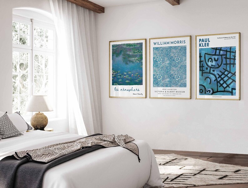 May include: Three framed art prints on a white wall. The prints feature artwork with blue and white colour schemes. The first print has the text "les n&eacute;nuphars". The second print has the text "WILLIAM MORRIS" and "VICTORIA & ALBERT MUSEUM". The third print has the text "PAUL KLEE".