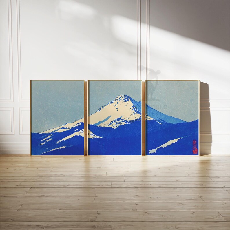 K&ouml;nnte beinhalten: Drei gerahmte Kunstdrucke, die eine schneebedeckte Berglandschaft in Blau- und Wei&szlig;t&ouml;nen zeigen. Das Kunstwerk ist im Stil eines Holzblockdrucks gehalten, mit einer minimalistischen &Auml;sthetik. Die Rahmen sind goldfarben.