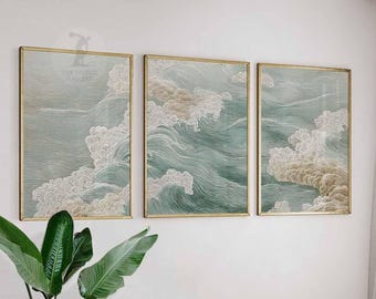 May include: Three framed art prints depicting stylized ocean waves in shades of teal, white, and beige. The artwork is encased in gold-colored frames. The overall theme is coastal and nature-inspired, suitable for home decor.