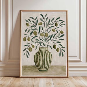May include: A framed art print depicting olive branches in a striped vase. The watercolour illustration features green olives and leaves against a neutral backdrop, framed in a light brown wooden frame. The artwork has a botanical theme.
