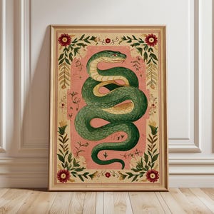 Könnte beinhalten: Gerahmter Kunstdruck mit einer grünen Schlangenillustration auf rosa Hintergrund. Die Schlange ist gewunden und detailliert, mit einem gelben Bauch. Das Kunstwerk ist in einem Holzrahmen mit floralen und botanischen Akzenten gerahmt.