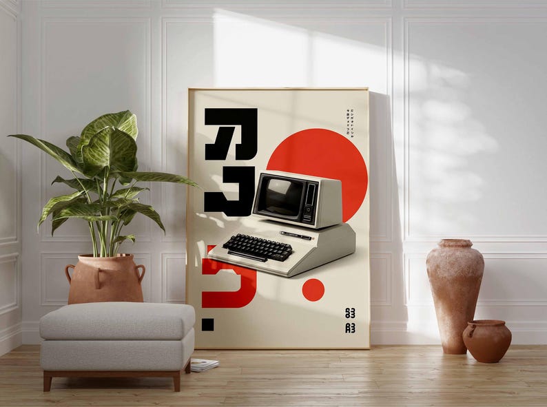 May include: A framed poster featuring a retro computer design with a black keyboard and monitor, a large red circle, and bold black typography. The poster is propped against a white wall, with a potted plant, ottoman, and decorative vases in the foreground.